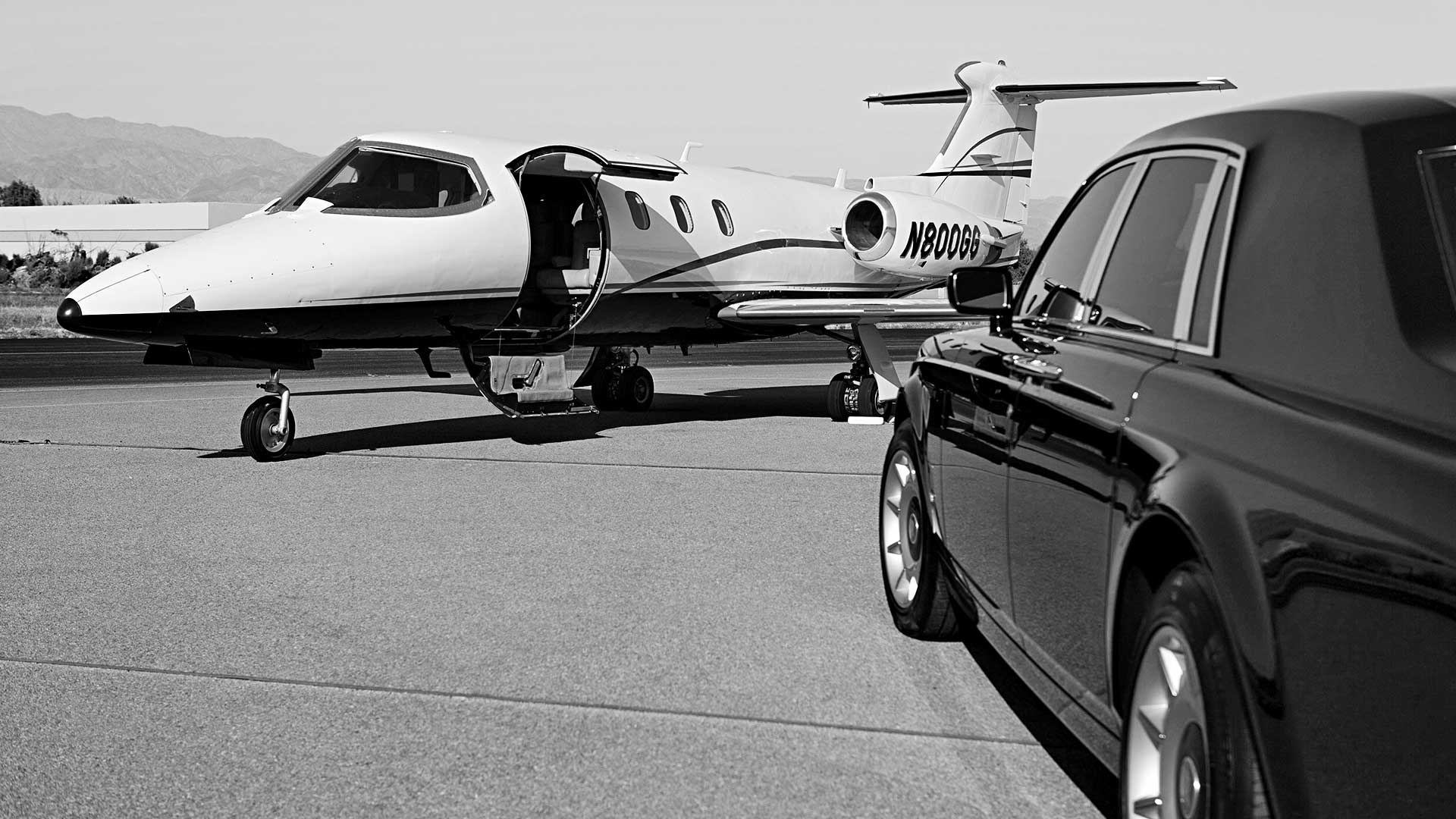 A black car waits beside a jet plane at the airport for its passenger